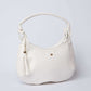 White leather handbag with tassel charm and gold-tone accent on plain background