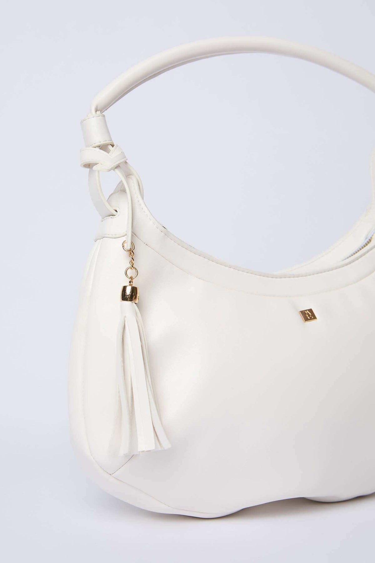 White shoulder bag with gold logo and tassel, elegant women's accessory