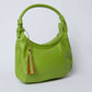 Green leather shoulder bag with zipper and multicolor tassel keychain on white background