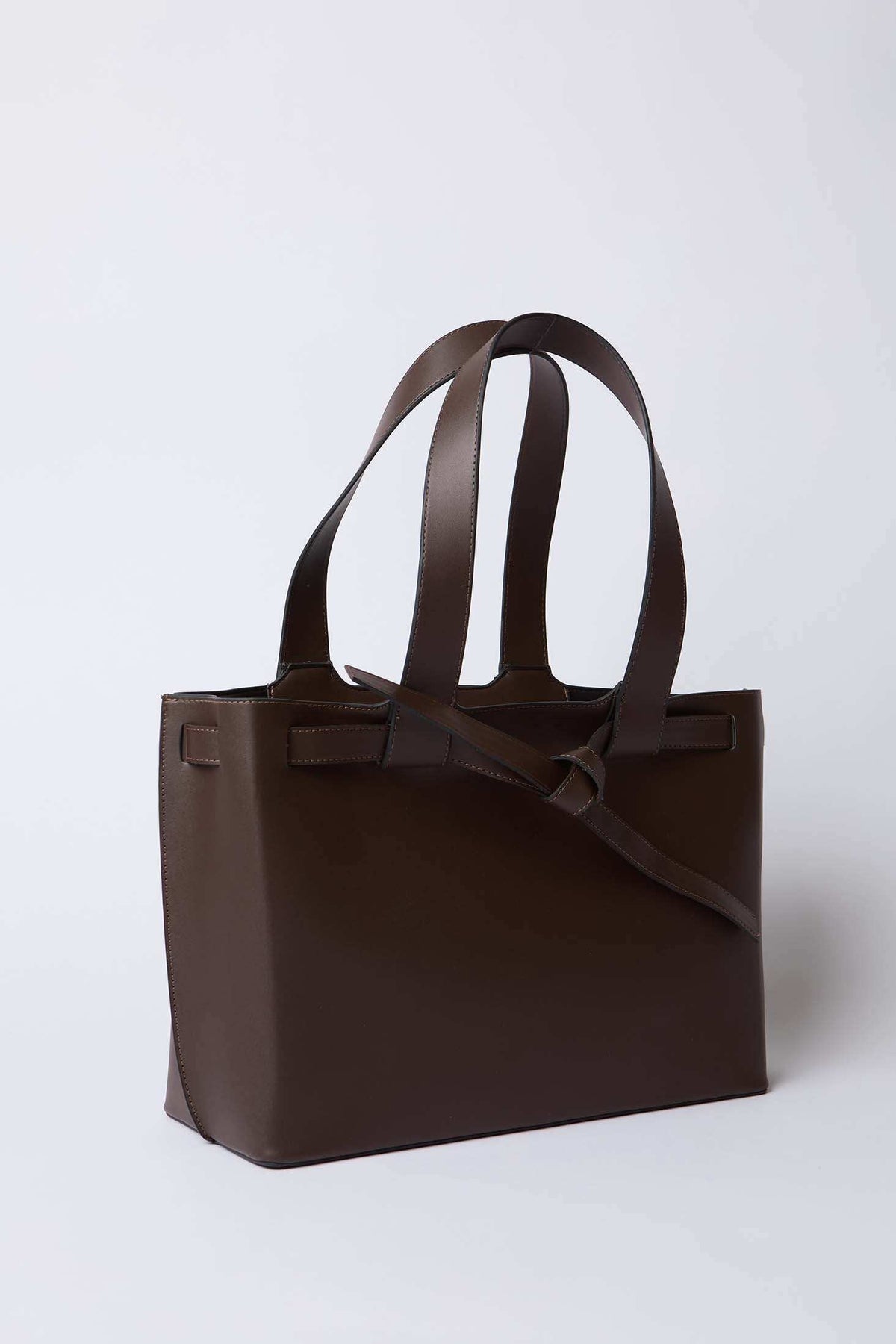 Brown leather tote bag with double handles and minimalist design on white background