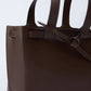 Close-up of brown leather tote bag with double handles and knotted detail on side