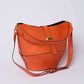 Orange leather shoulder bag with gold-tone hardware and adjustable strap on white background