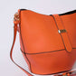 Orange leather shoulder bag with gold buckle and adjustable strap, modern women's accessory