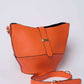 Orange leather bucket bag with adjustable strap and gold buckle on a plain background
