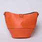 Orange leather bucket bag with gold hardware on a plain background