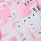 Abstract pink and white fabric with geometric building and window print pattern.