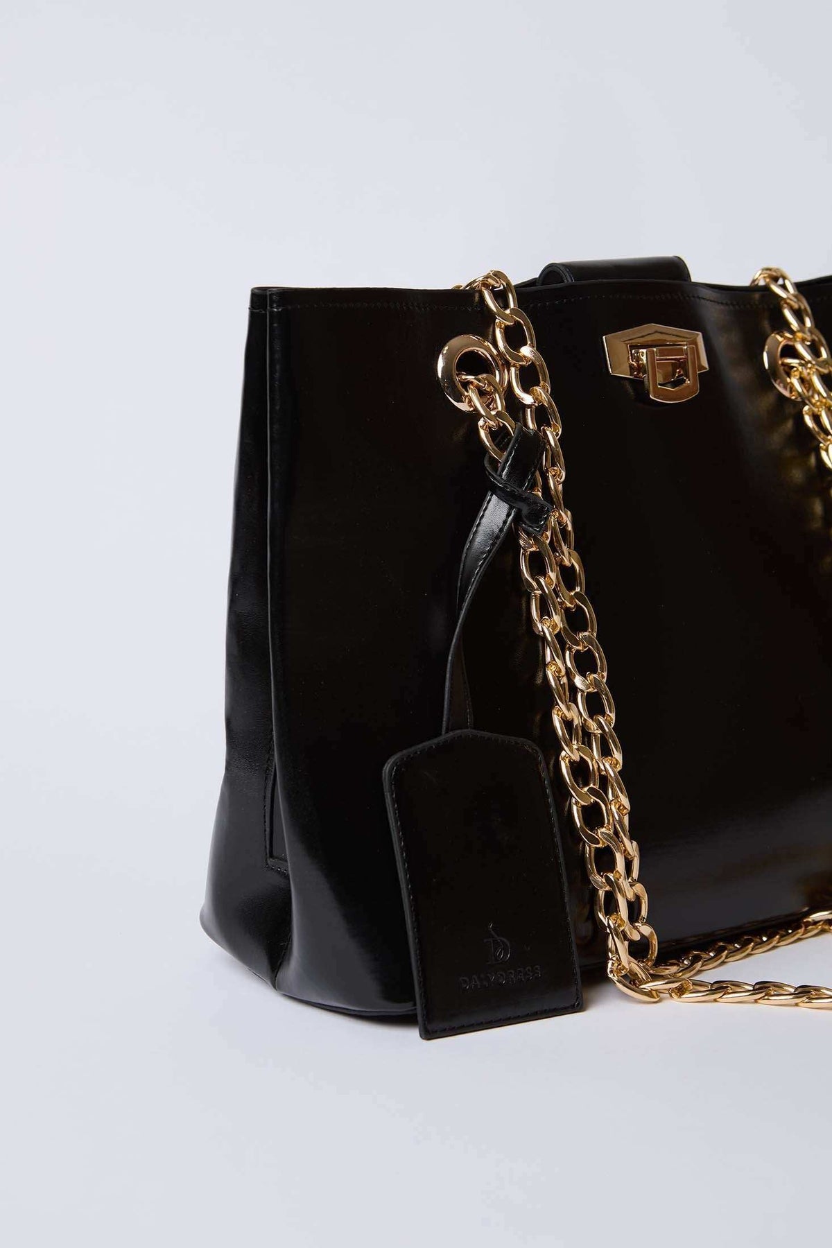 Dalydress black leather handbag with gold chain strap and logo tag on white background